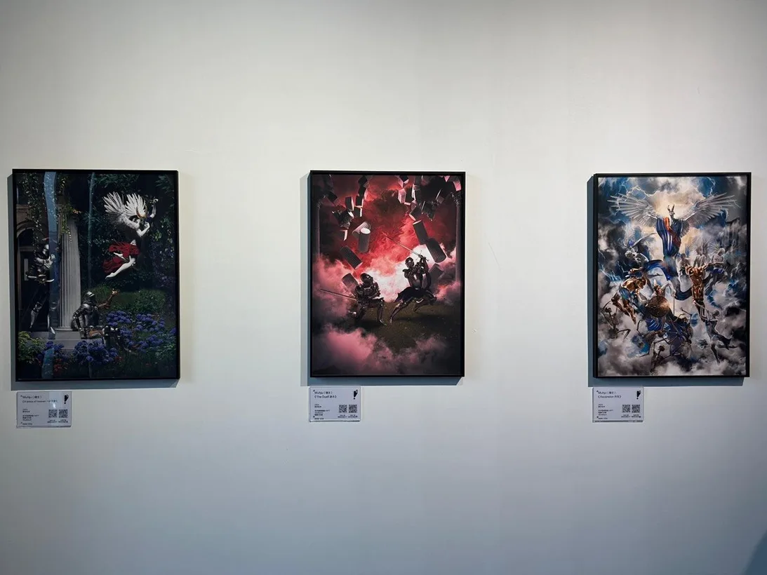 Three framed Muhju artworks hang with small labels on a white gallery wall.
