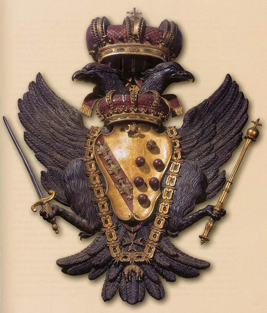 A black double-headed eagle holding the crowned Medici shield, a sword and a sceptre.