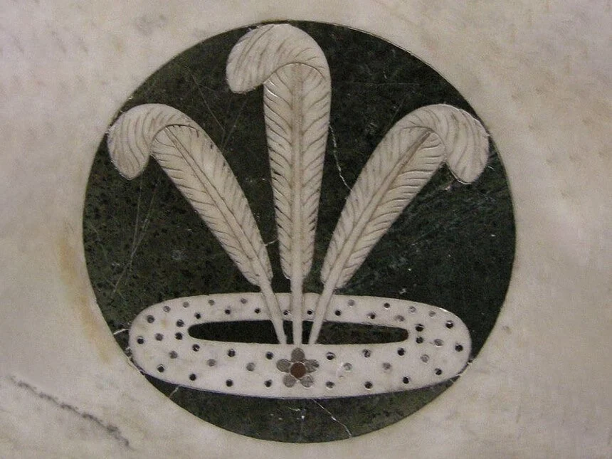 A marble roundel with three white feathers rising from a ring.